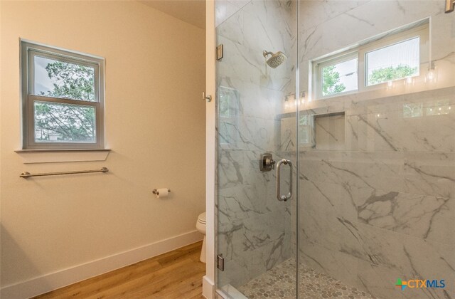 bathroom featuring walk in shower, plenty of natural light, hardwood / wood-style flooring, and toilet