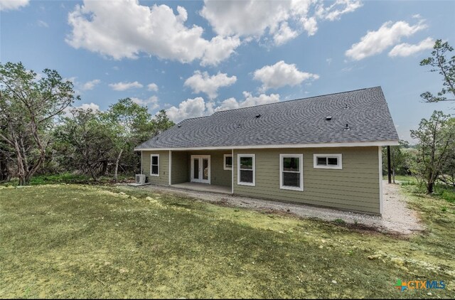 rear view of house with cooling unit, a lawn, and a patio area