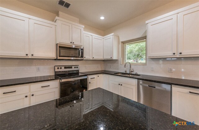 kitchen featuring dark stone countertops, white cabinets, sink, and stainless steel appliances