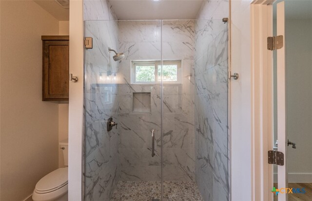 bathroom featuring a shower with shower door and toilet