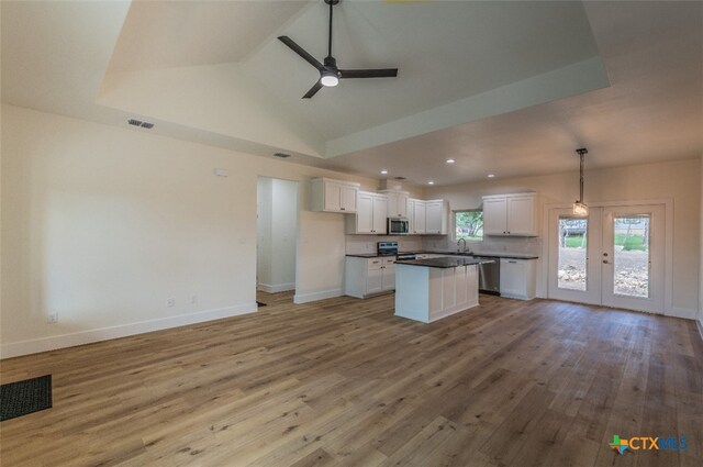 kitchen with stainless steel appliances, white cabinetry, ceiling fan, decorative light fixtures, and light hardwood / wood-style flooring