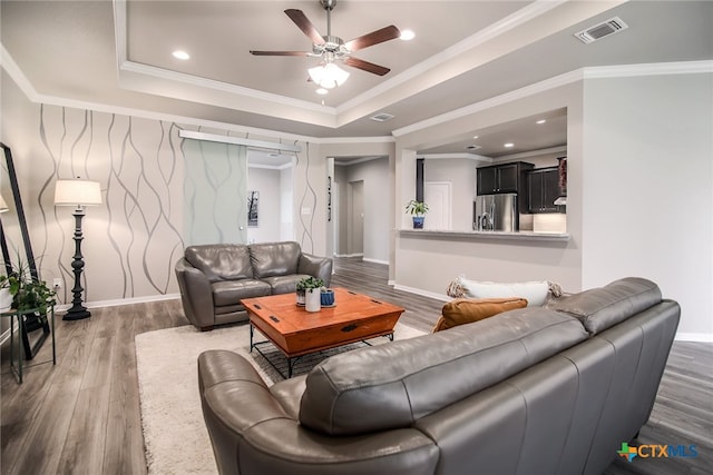 living room with a tray ceiling, crown molding, and dark hardwood / wood-style floors