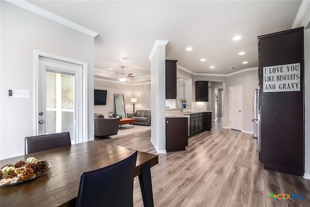 dining area with light hardwood / wood-style floors, ceiling fan, crown molding, and sink