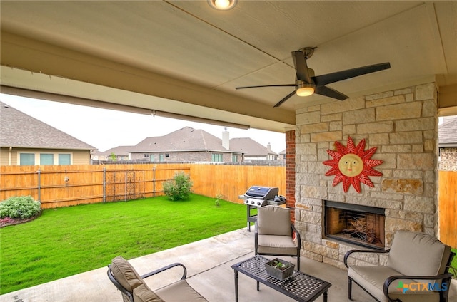 view of patio with an outdoor stone fireplace, ceiling fan, and grilling area