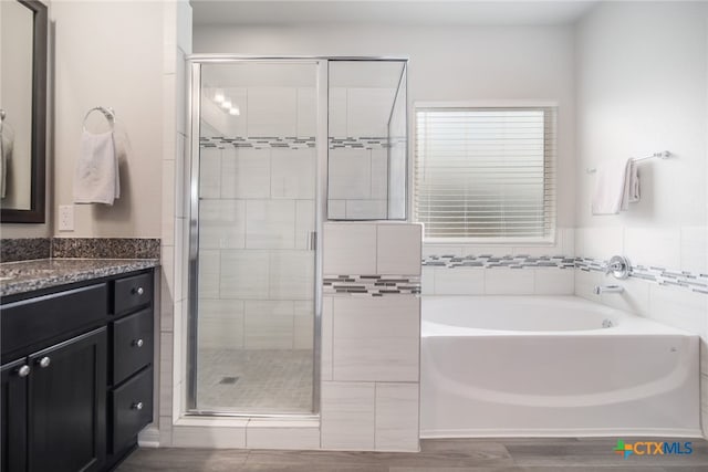 bathroom with hardwood / wood-style floors, vanity, and shower with separate bathtub