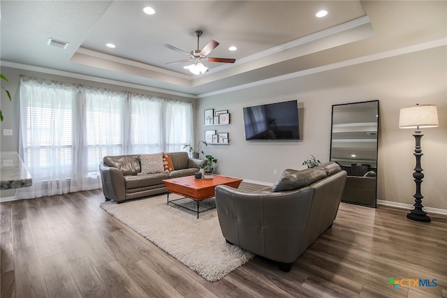 living room featuring wood-type flooring, a raised ceiling, ceiling fan, and ornamental molding