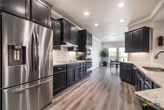 kitchen featuring sink, hardwood / wood-style flooring, ornamental molding, appliances with stainless steel finishes, and tasteful backsplash