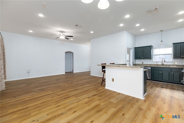 kitchen featuring decorative light fixtures, a kitchen island, light hardwood / wood-style floors, and sink