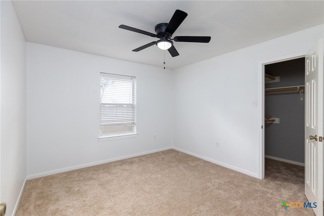 unfurnished bedroom featuring ceiling fan, a walk in closet, light carpet, and a closet