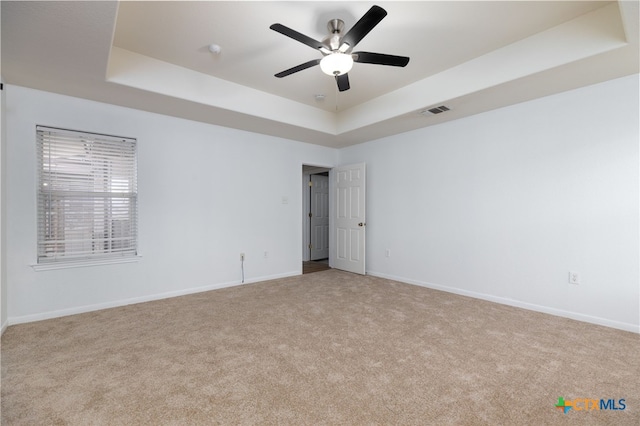 carpeted empty room with a tray ceiling and ceiling fan