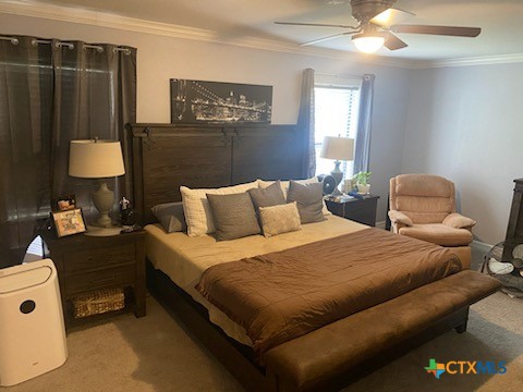 bedroom featuring light carpet, ceiling fan, and crown molding