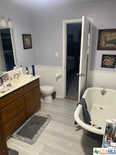 bathroom with toilet, a tub to relax in, and vanity