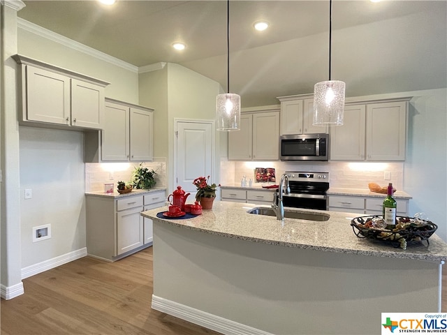 kitchen with stainless steel appliances, sink, light stone counters, hanging light fixtures, and light wood-type flooring