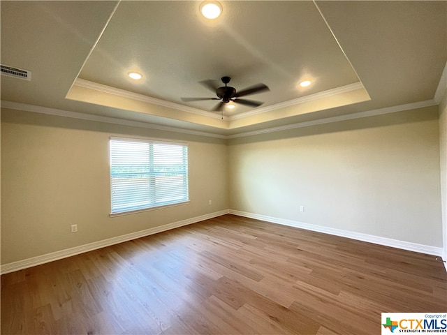 spare room with wood-type flooring, a raised ceiling, and ornamental molding