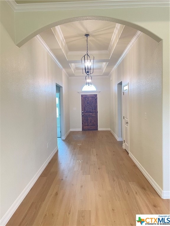 interior space featuring ornamental molding, light hardwood / wood-style floors, a raised ceiling, and an inviting chandelier