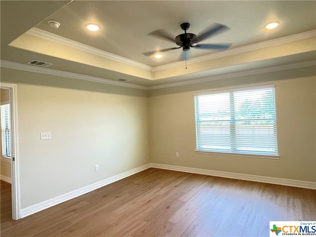 unfurnished room featuring hardwood / wood-style floors, a raised ceiling, ceiling fan, and crown molding