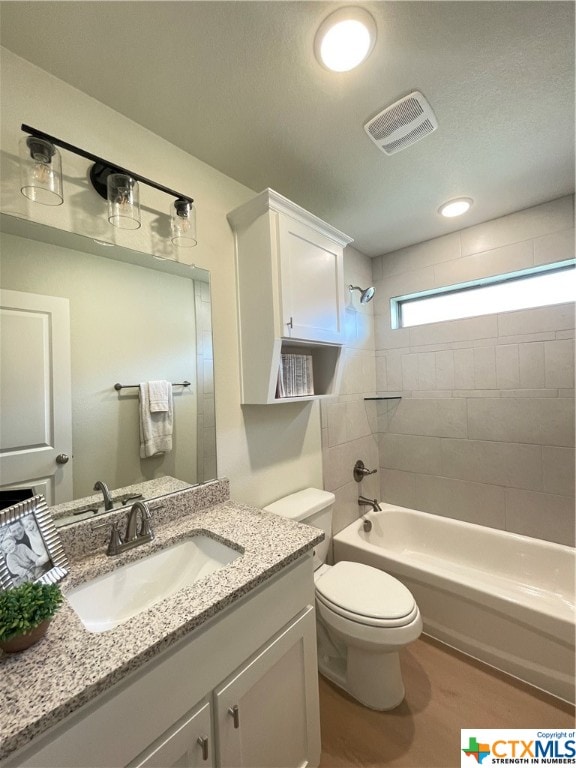 full bathroom with hardwood / wood-style floors, tiled shower / bath, toilet, and vanity