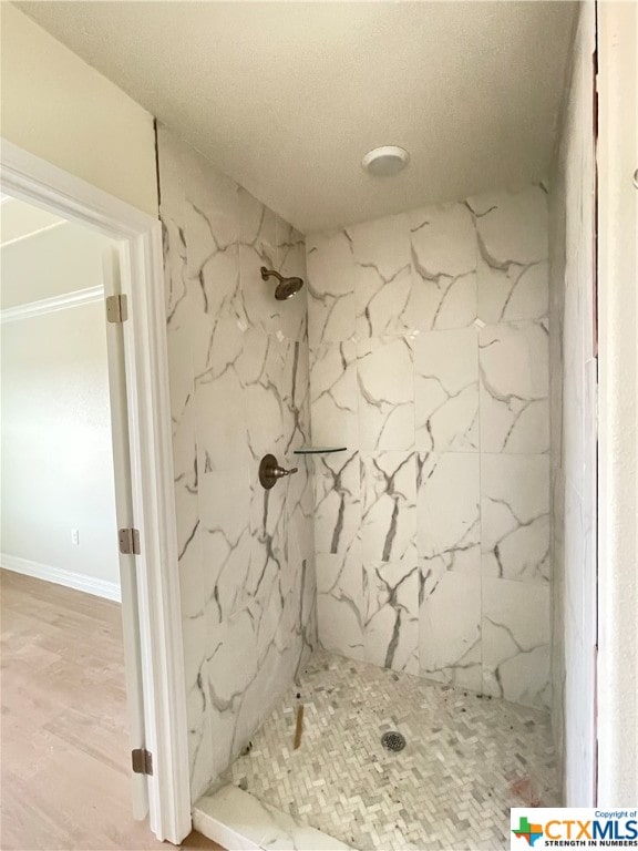 bathroom featuring hardwood / wood-style floors and a tile shower