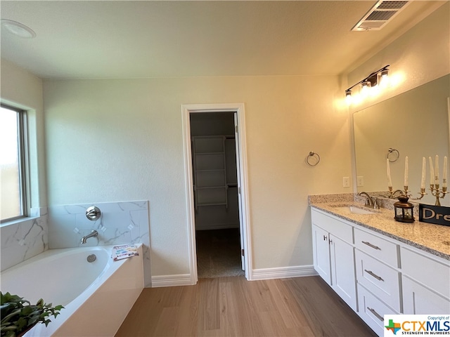 bathroom with hardwood / wood-style flooring, vanity, and a tub