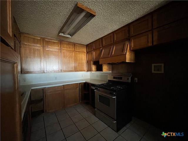 kitchen featuring light tile patterned flooring, a textured ceiling, and stainless steel gas range