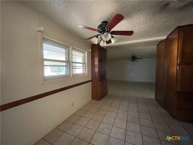 tiled empty room featuring ceiling fan and a textured ceiling