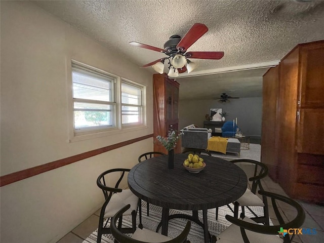 dining space featuring ceiling fan and a textured ceiling