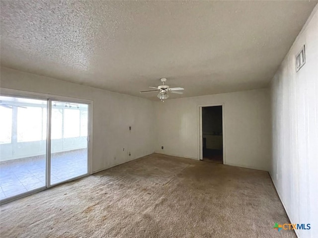 empty room with carpet flooring, ceiling fan, and a textured ceiling