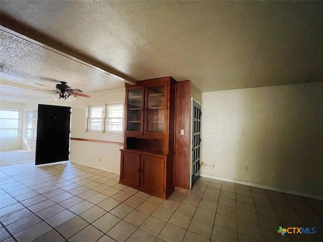 unfurnished living room featuring ceiling fan, light tile patterned flooring, and a textured ceiling