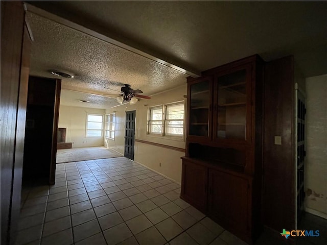 interior space with ceiling fan, light tile patterned floors, and a textured ceiling