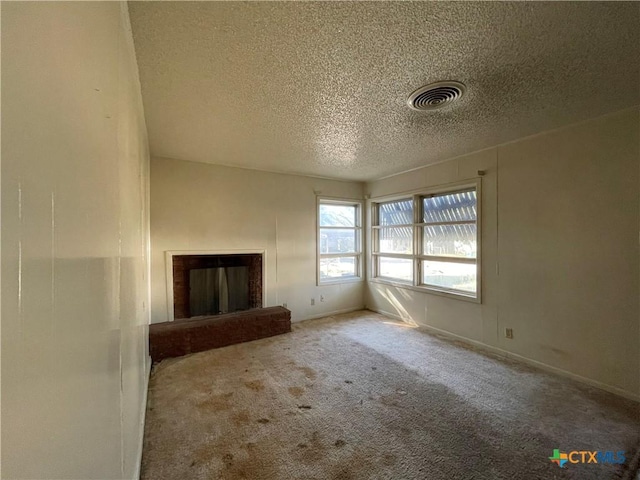 unfurnished living room with carpet flooring, a textured ceiling, and a brick fireplace