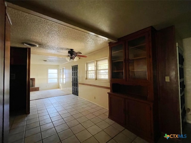 interior space with a textured ceiling, ceiling fan, and light tile patterned flooring