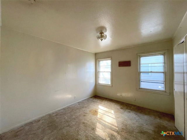 carpeted empty room featuring a textured ceiling