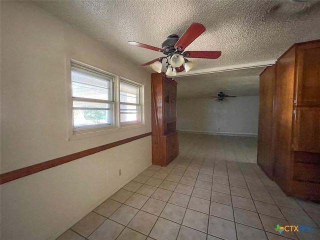 unfurnished room featuring ceiling fan, light tile patterned flooring, and a textured ceiling