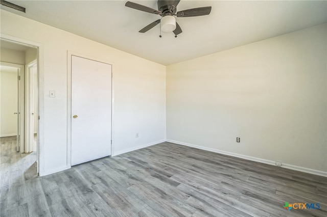 unfurnished bedroom featuring ceiling fan, a closet, and light wood-type flooring