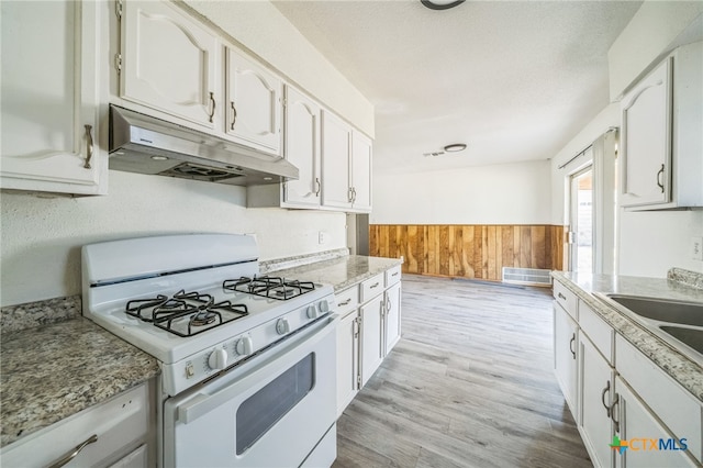 kitchen featuring white cabinets, white gas stove, and light hardwood / wood-style flooring