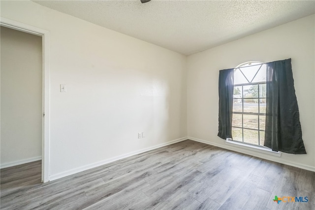 unfurnished room featuring light hardwood / wood-style flooring and a textured ceiling