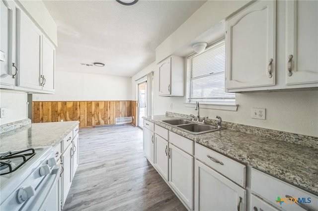 kitchen featuring white range oven, white cabinetry, and sink