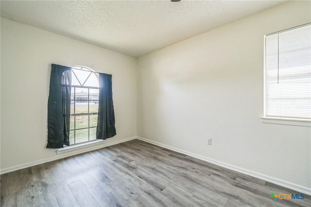 empty room featuring a textured ceiling and light hardwood / wood-style flooring