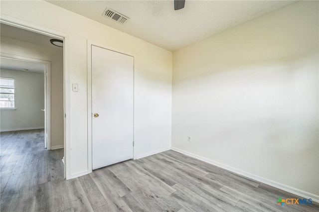 unfurnished bedroom featuring ceiling fan, a textured ceiling, and light hardwood / wood-style flooring