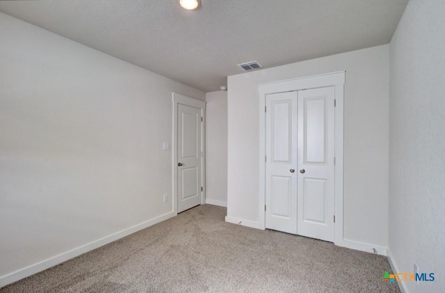 unfurnished bedroom with light carpet and a closet