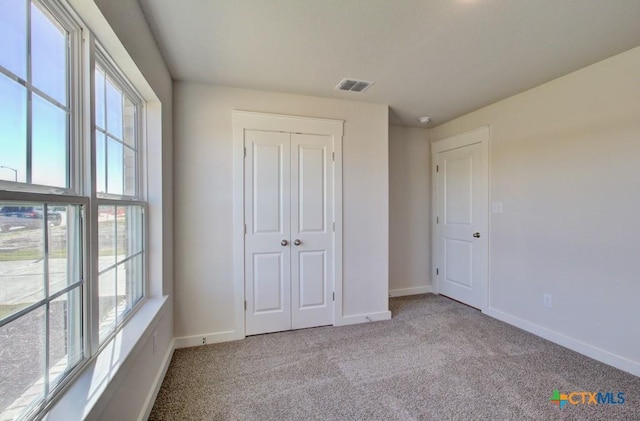 unfurnished bedroom featuring light colored carpet and a closet