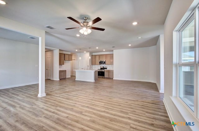 unfurnished living room with ceiling fan, a healthy amount of sunlight, light wood-type flooring, and sink