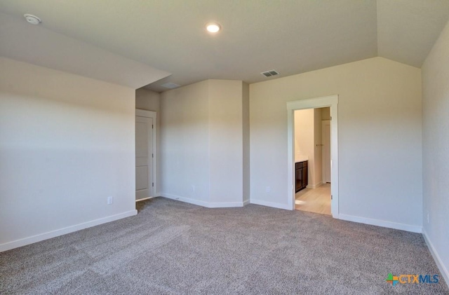 carpeted spare room featuring vaulted ceiling