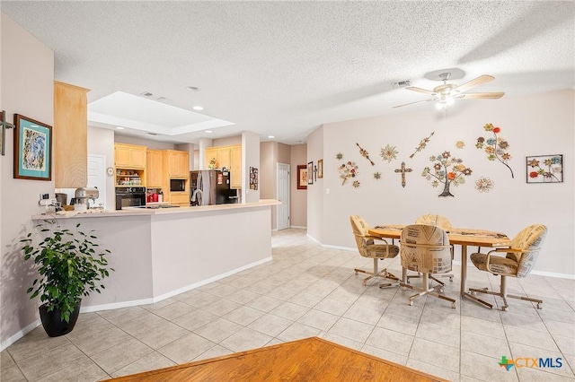 621 Brocton St, Victoria, TX 77904 - kitchen with light brown cabinets, freestanding refrigerator, a ceiling fan, black microwave, and light tile patterned floors