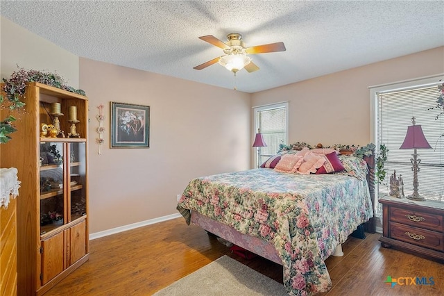 bedroom with ceiling fan, dark hardwood / wood-style flooring, multiple windows, and a textured ceiling