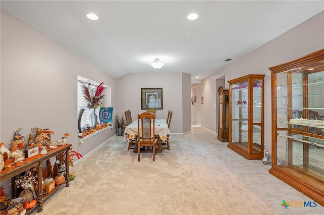 dining space featuring a textured ceiling, light carpet, and vaulted ceiling