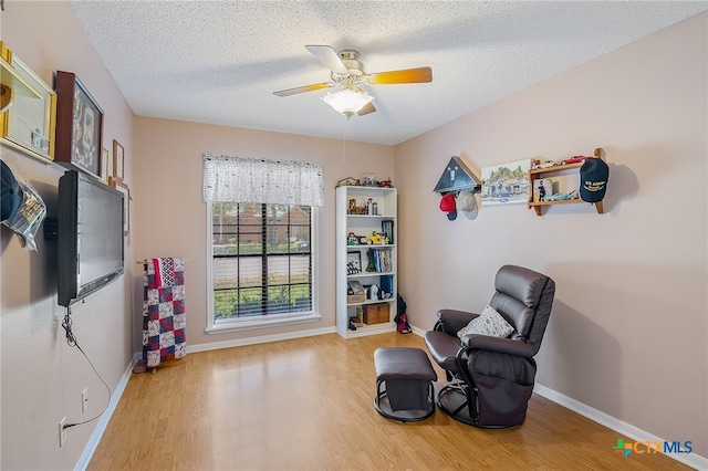 living area with a textured ceiling, light hardwood / wood-style floors, and ceiling fan