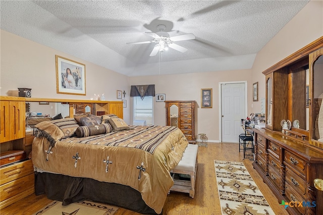 bedroom featuring light hardwood / wood-style floors, ceiling fan, a textured ceiling, and vaulted ceiling