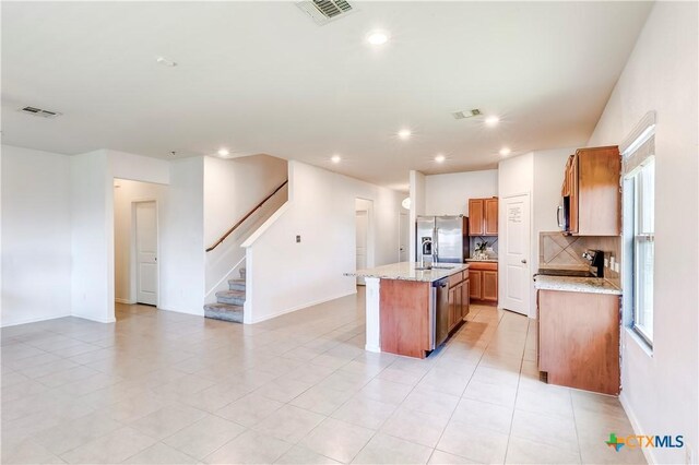 3802 Endicott Dr, Killeen, TX 76549 - kitchen featuring appliances with stainless steel finishes, an island with sink, tasteful backsplash, brown cabinets, and recessed lighting