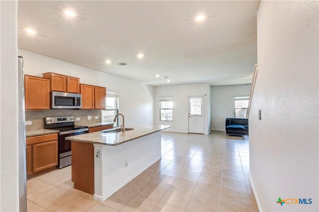 3802 Endicott Dr, Killeen, TX 76549 - kitchen featuring stainless steel appliances, brown cabinetry, backsplash, light tile patterned flooring, and light stone counters